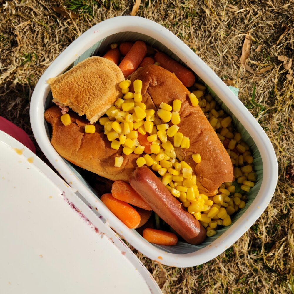 Compost bucket full of hot dogs and corn.