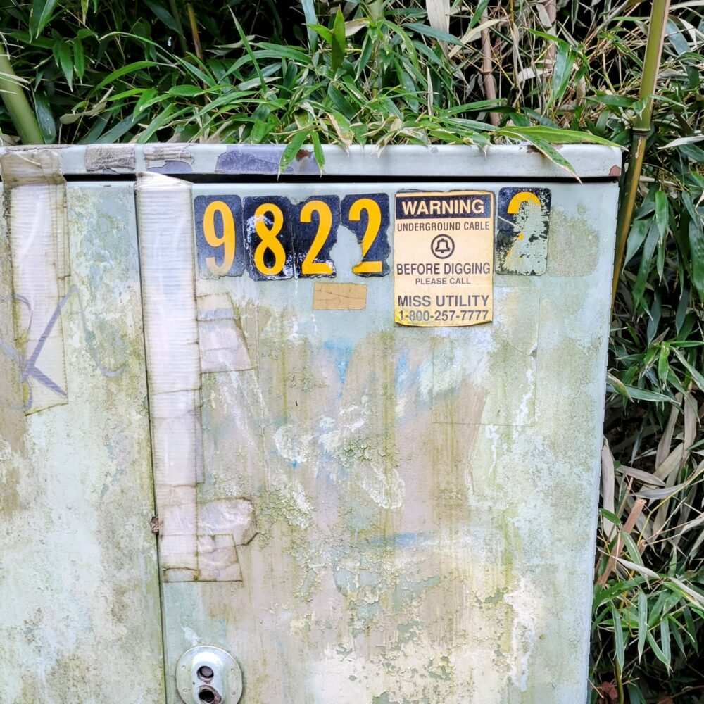 Utility box covered in layers of graffiti and cover-up paint.
