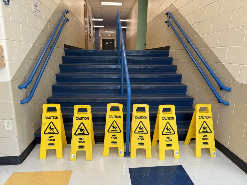 Some yellow wet floor signs blocking a blue staircase. 