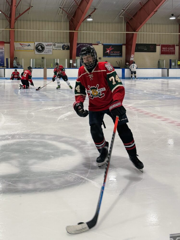 An aging hockey player in a red jersey, chasing a puck.