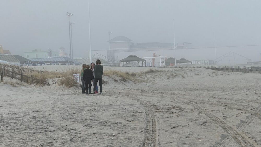 A group of kids huddled at the beach.